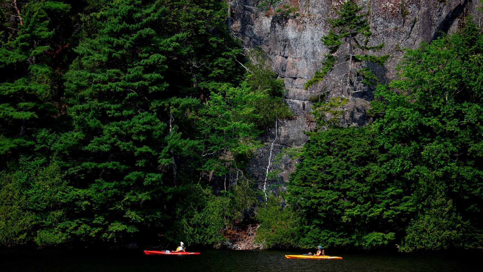 Kayakers paddle by cliffs along Echo Lake