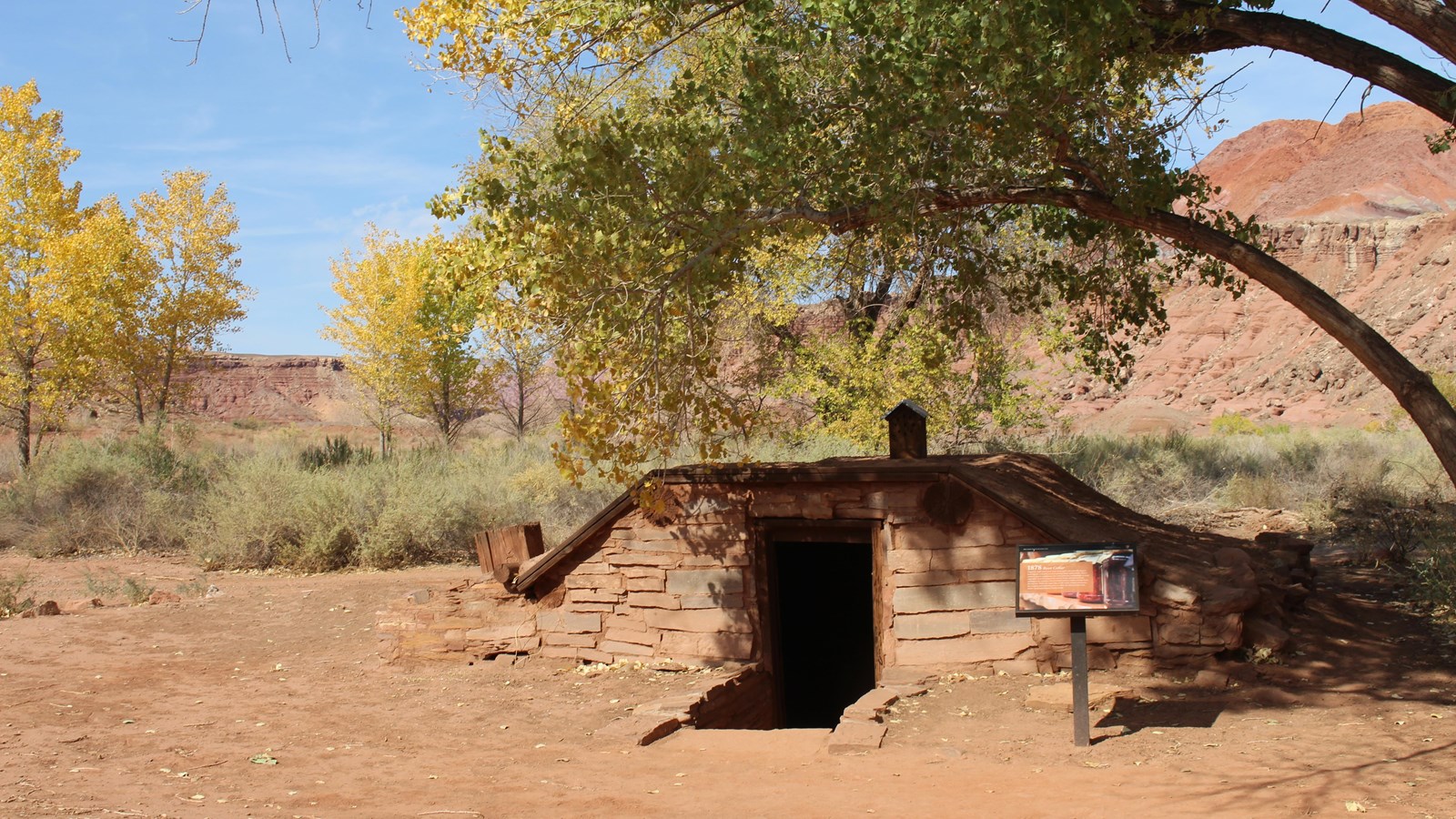 Interpretive sign outside of wooden root cellar. 