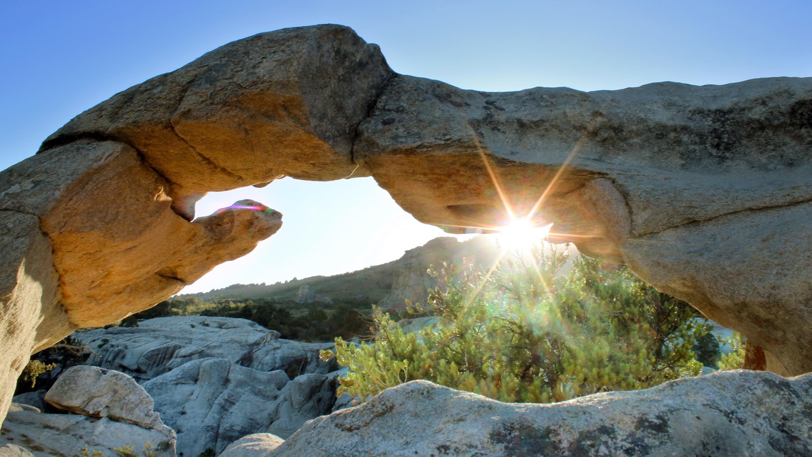 Rays of sunshine peek through the archway revealing a grand view of City of Rocks.
