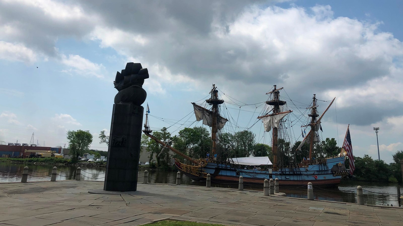 A wooden ship sails past a monument. 
