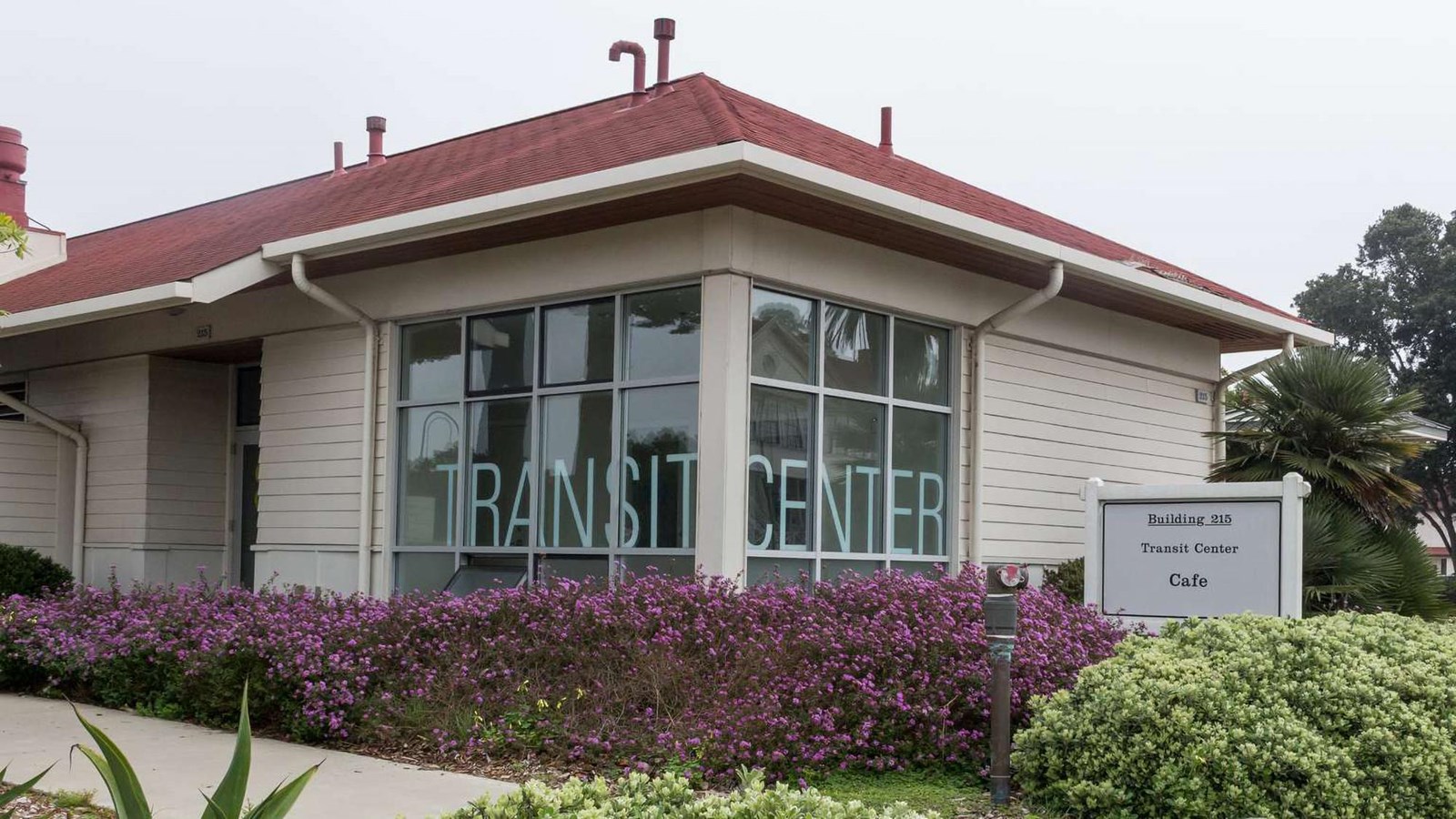 Exterior of the former Presidio Transit Center with blooming bushes in front.