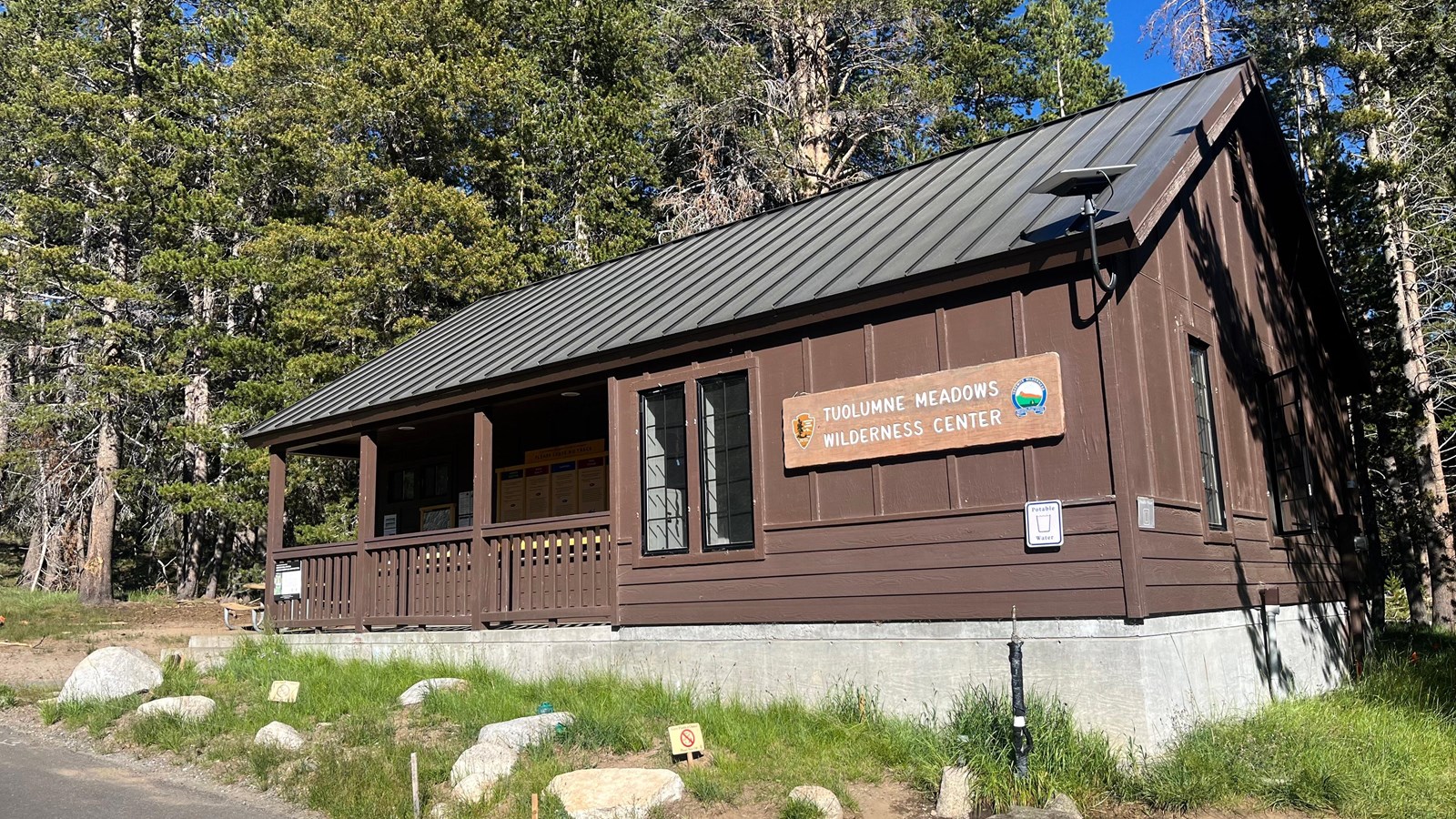 A brown building with a covered entry and a sign that says