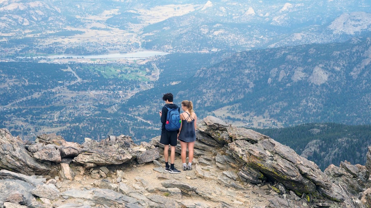 two people standing on a mountain top taking in the view
