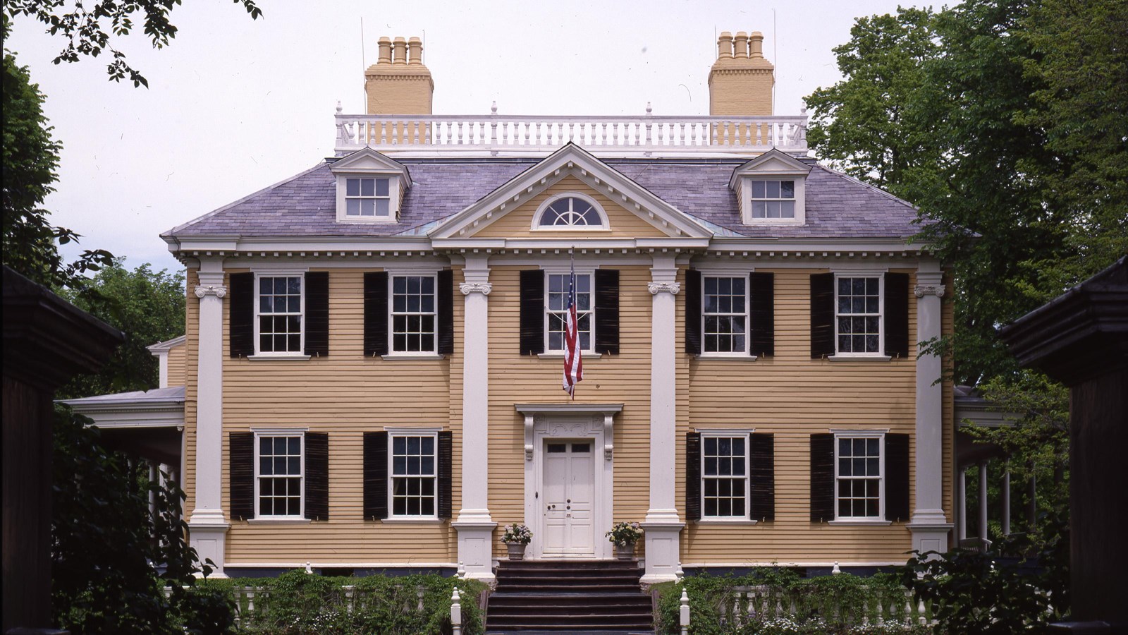 Large three-story yellow house with symmetrical facade, 12 windows, and two chimneys