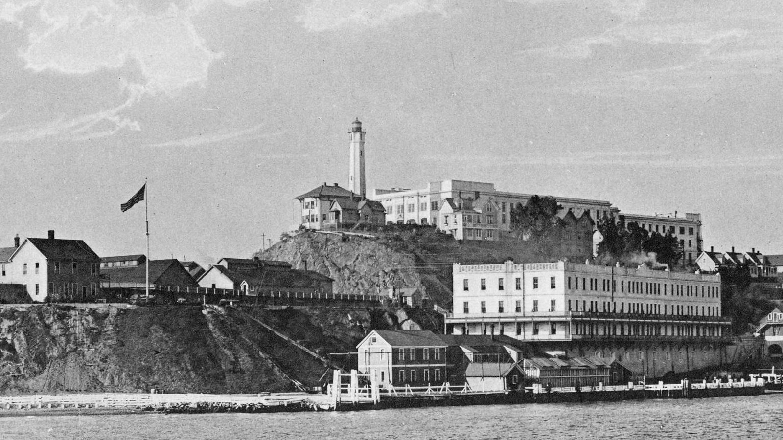 Buildings covering rocky island. A striped flag flies above several buildings.