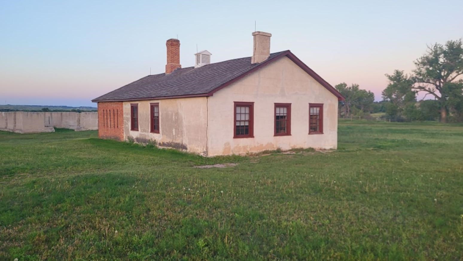 Image of lime rout brick building with two chimneys and five small floor level windows.