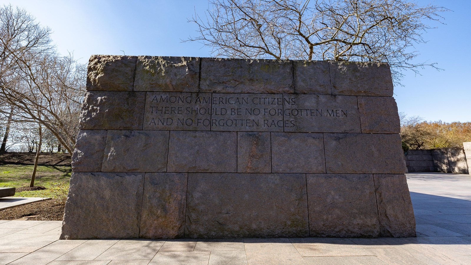 A tall, stone wall has words engraved said by Franklin Roosevelt.