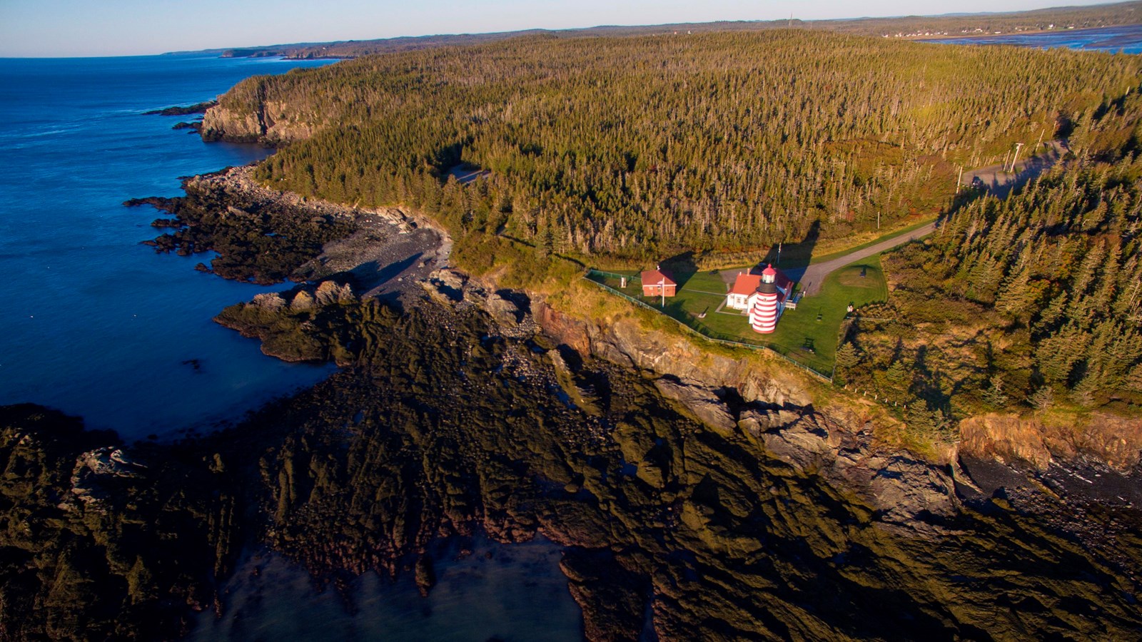 Small house on green slope next to blue sea
