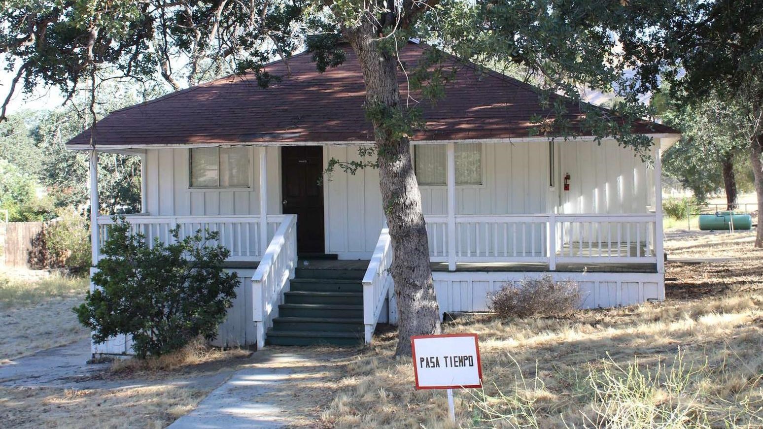 A small white house under oak trees.