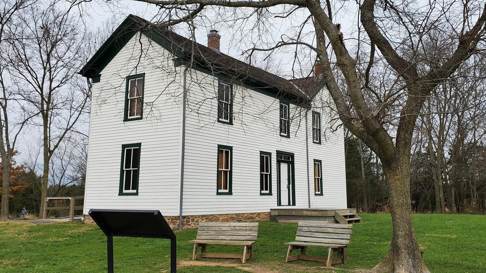 Image of the Brawner Farm Interpretive Center with a lone tree and benches in the foreground