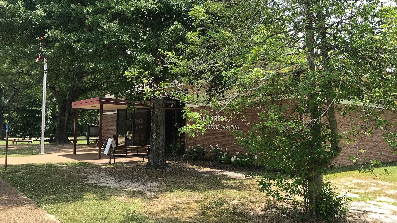 A one story brick building surrounded by large trees. 