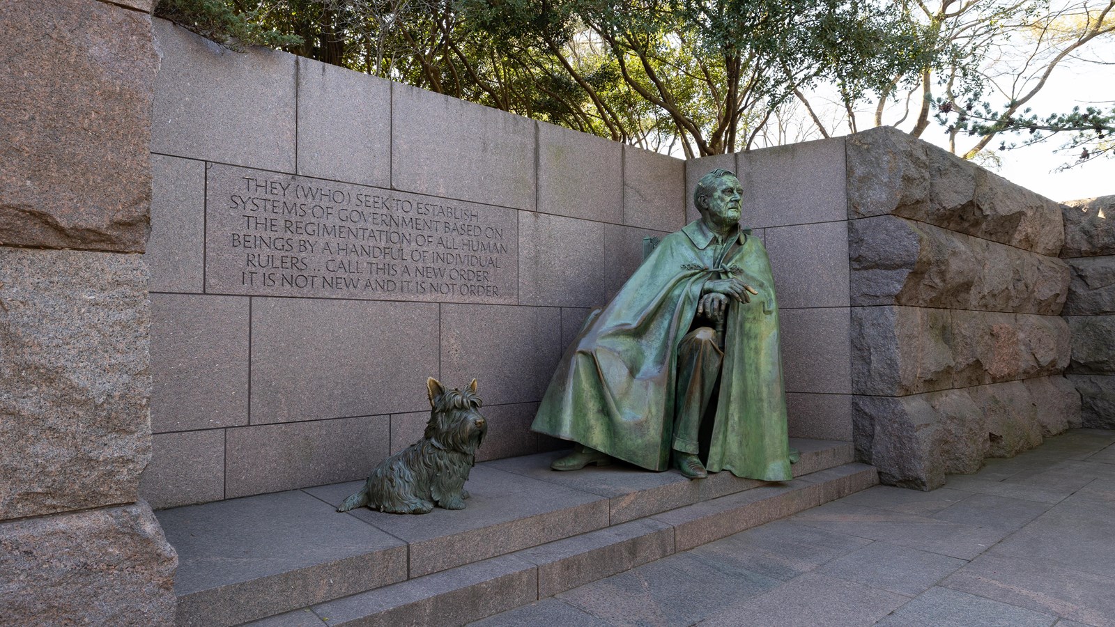 A statue of a dog is positioned next to a statue of FDR in a wheelchair. 