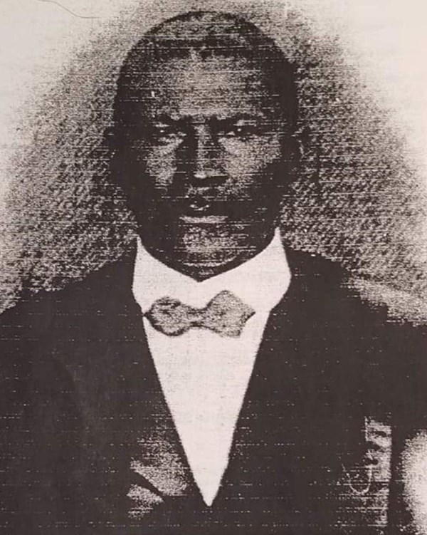 Scan of image of black man with mustache and wearing a black suite with a bow tie