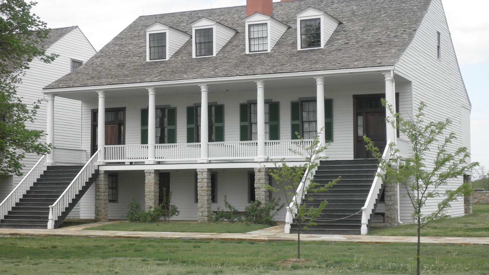 two story building with pillars, stairs on both sides, windows on roof