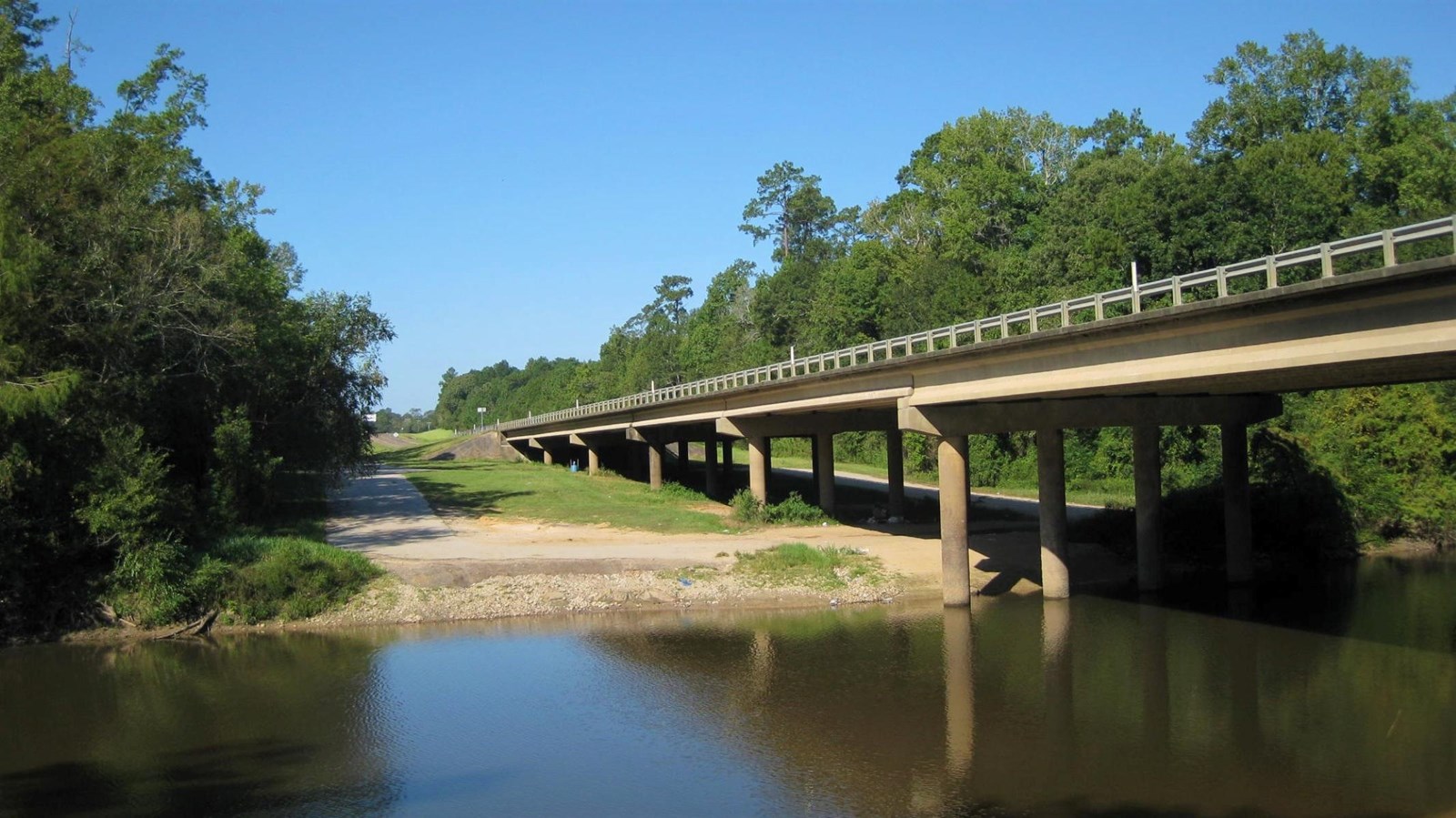 highway bridge over a river and sandy boat launch area