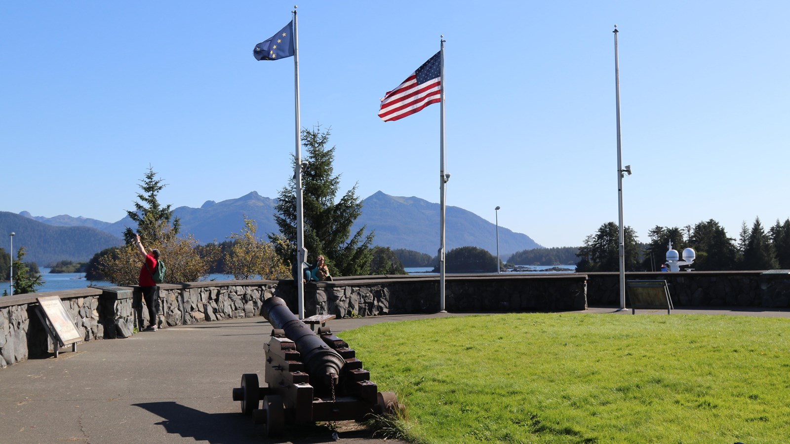 American and Alaska State Flags at full staff against a bright blue sky.
