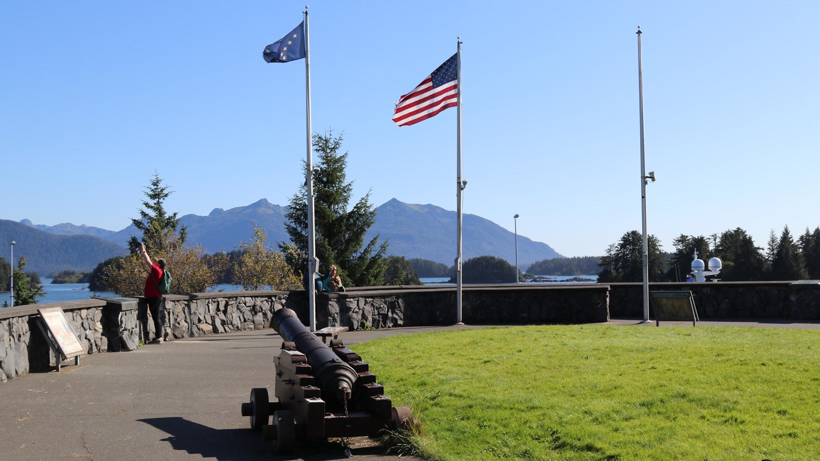 American and Alaska State Flags at full staff against a bright blue sky.
