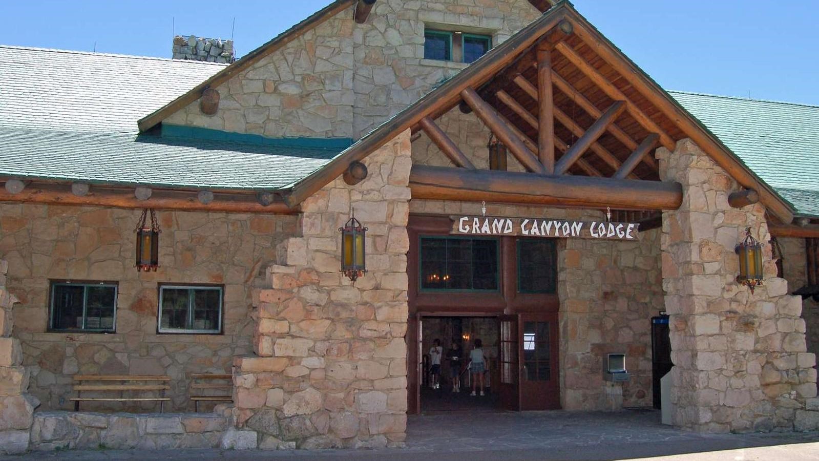 Entrance to a rustic stone lodge with wooden beams, peaked roof, and a gabled arch.