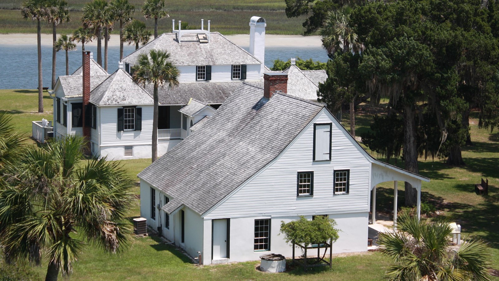 white two story kitchen house seen from above with another white house just behind then a river