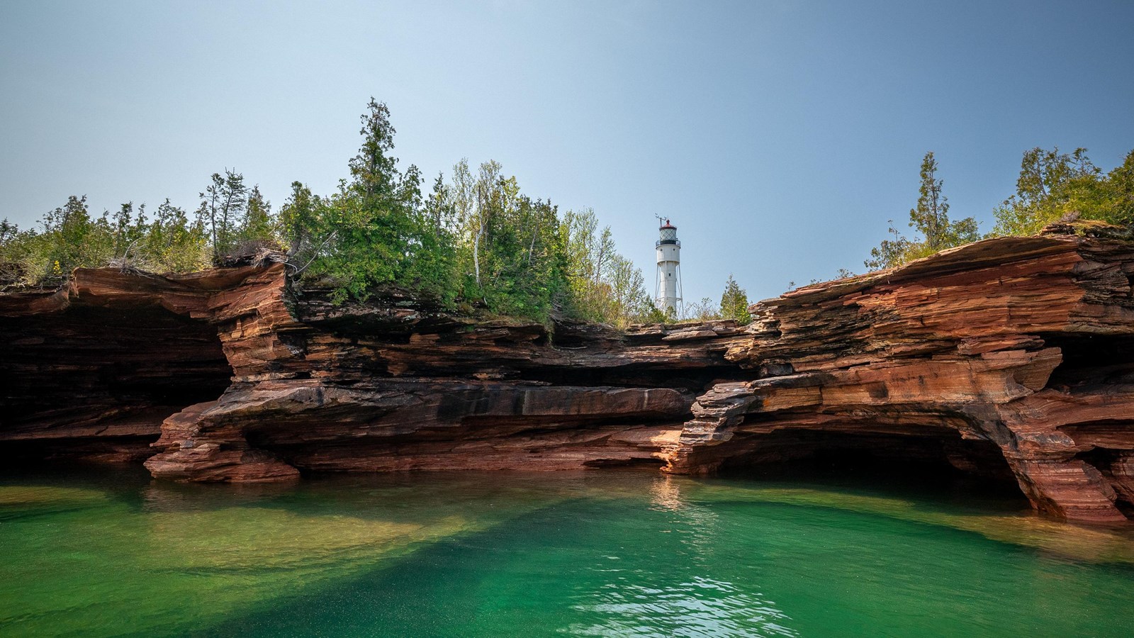 Photograph of sandstone sea caves and lighthouse.