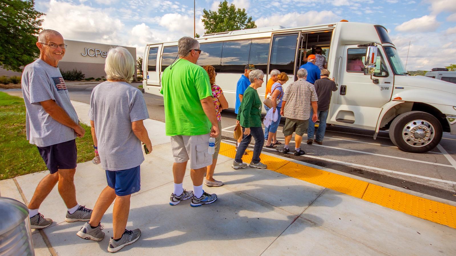 Several people boarding a small bus.