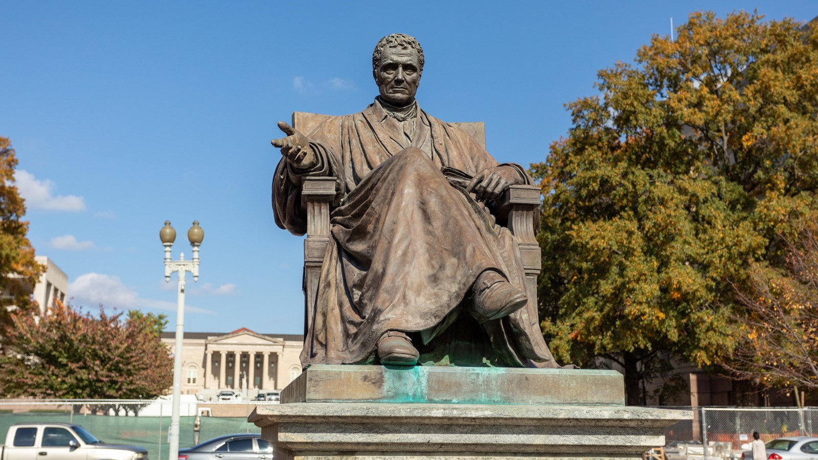 Bronze statue of man in judicial robes, seated on a stone plinth.