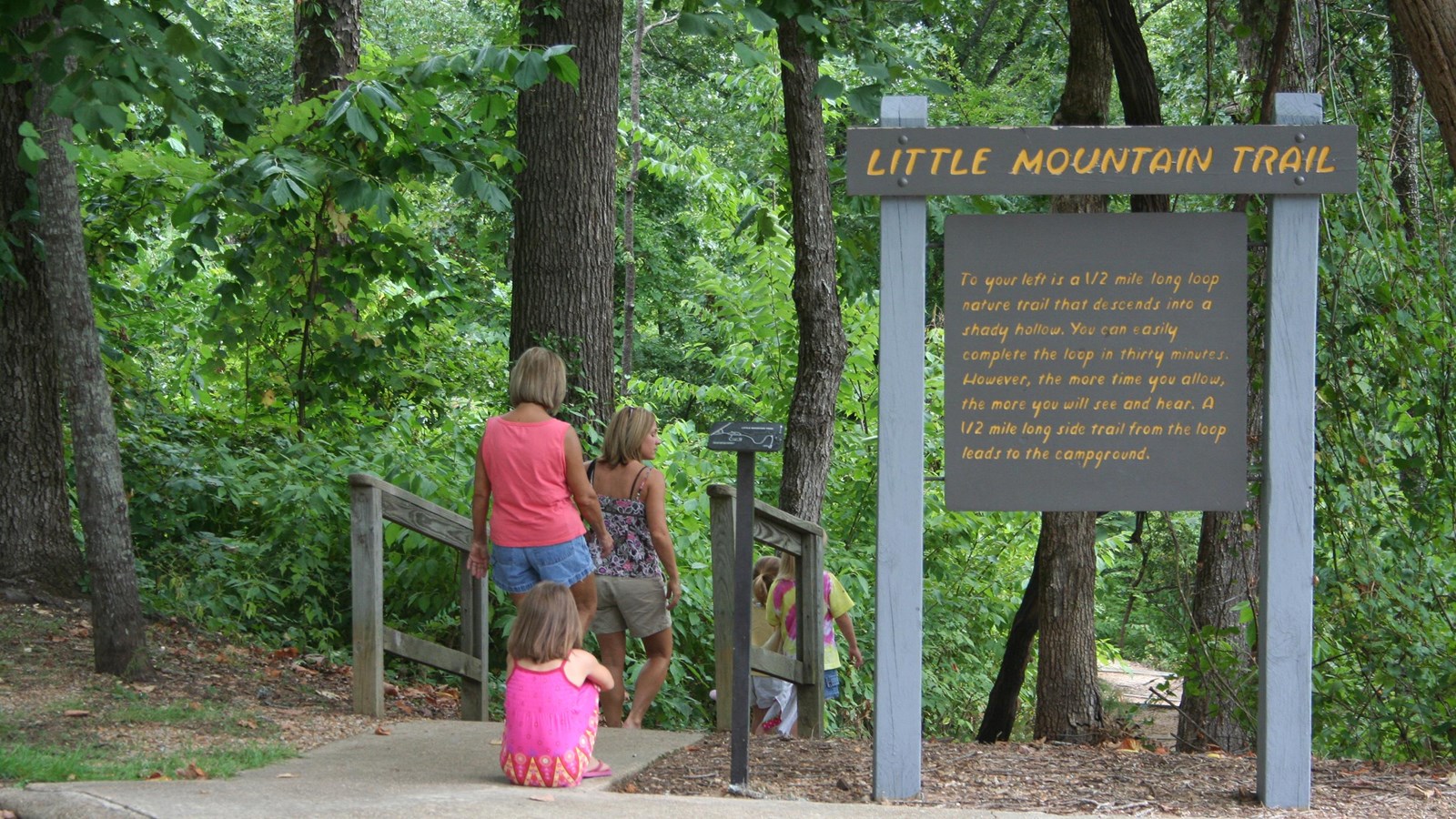 A family heading down step on a trail with a sign that says Little Mountain Trail