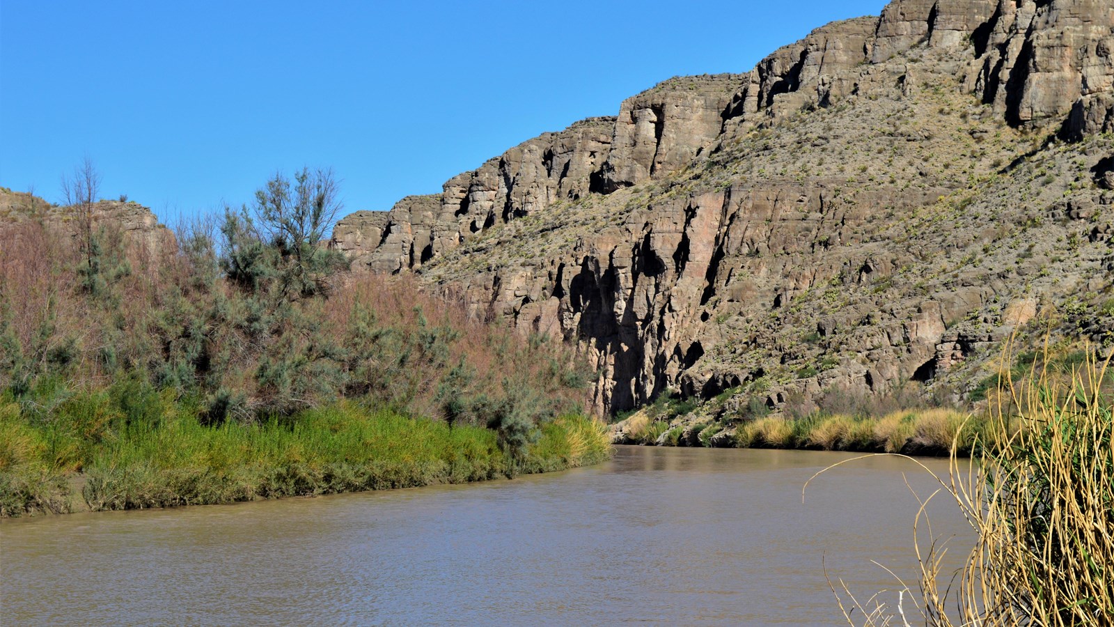 The Rio Grande flows around a bend, contouring along a limestone bluff.
