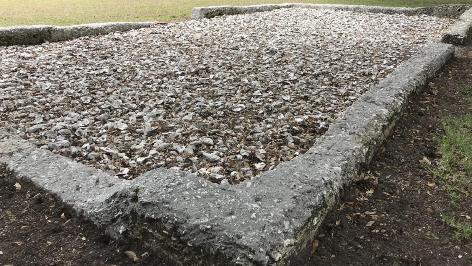 Tabby exterior wall foundation with oyster shells filling the interior and grass surounding.