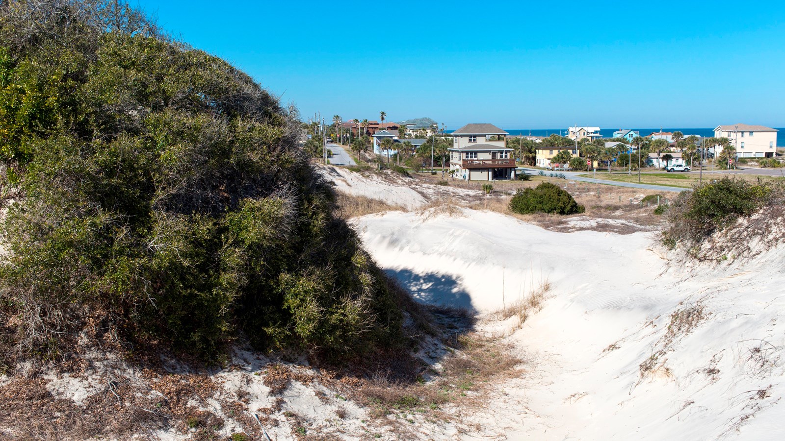 a large dune over looks beach house and the ocean