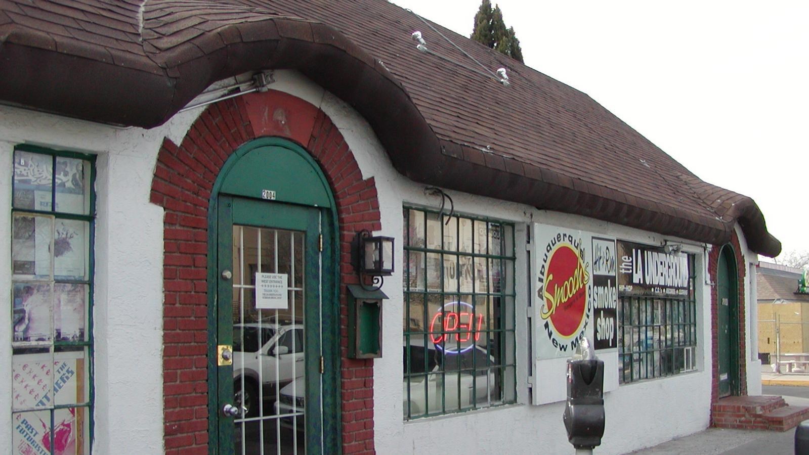 A white building with a brown roof that arches over the front doors.