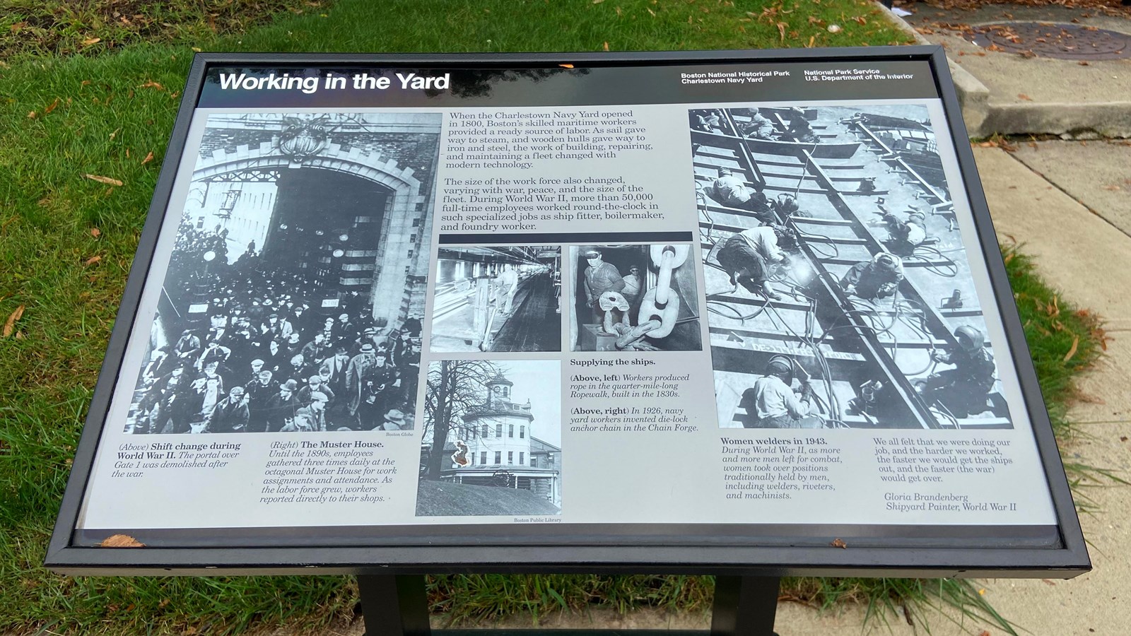 A wayside with black and white pictures depicting people working at the navy yard in different roles