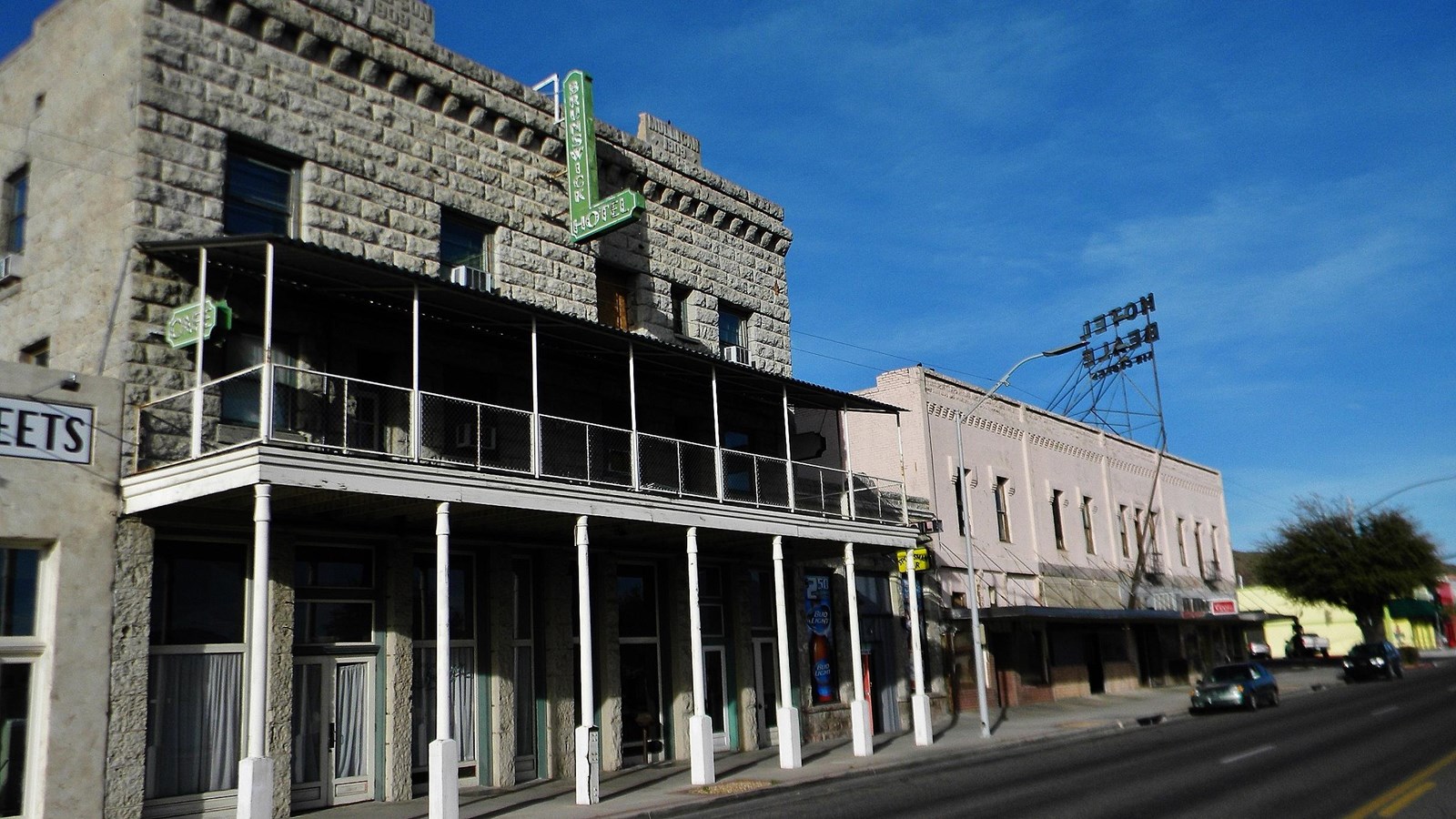 A two story grey building with a covered patio held up by white pillars.