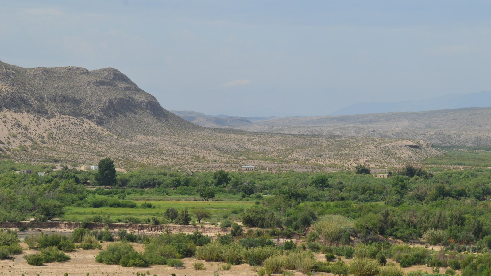 Six buildings are visible in the distance, on the other side of the Rio Grande.