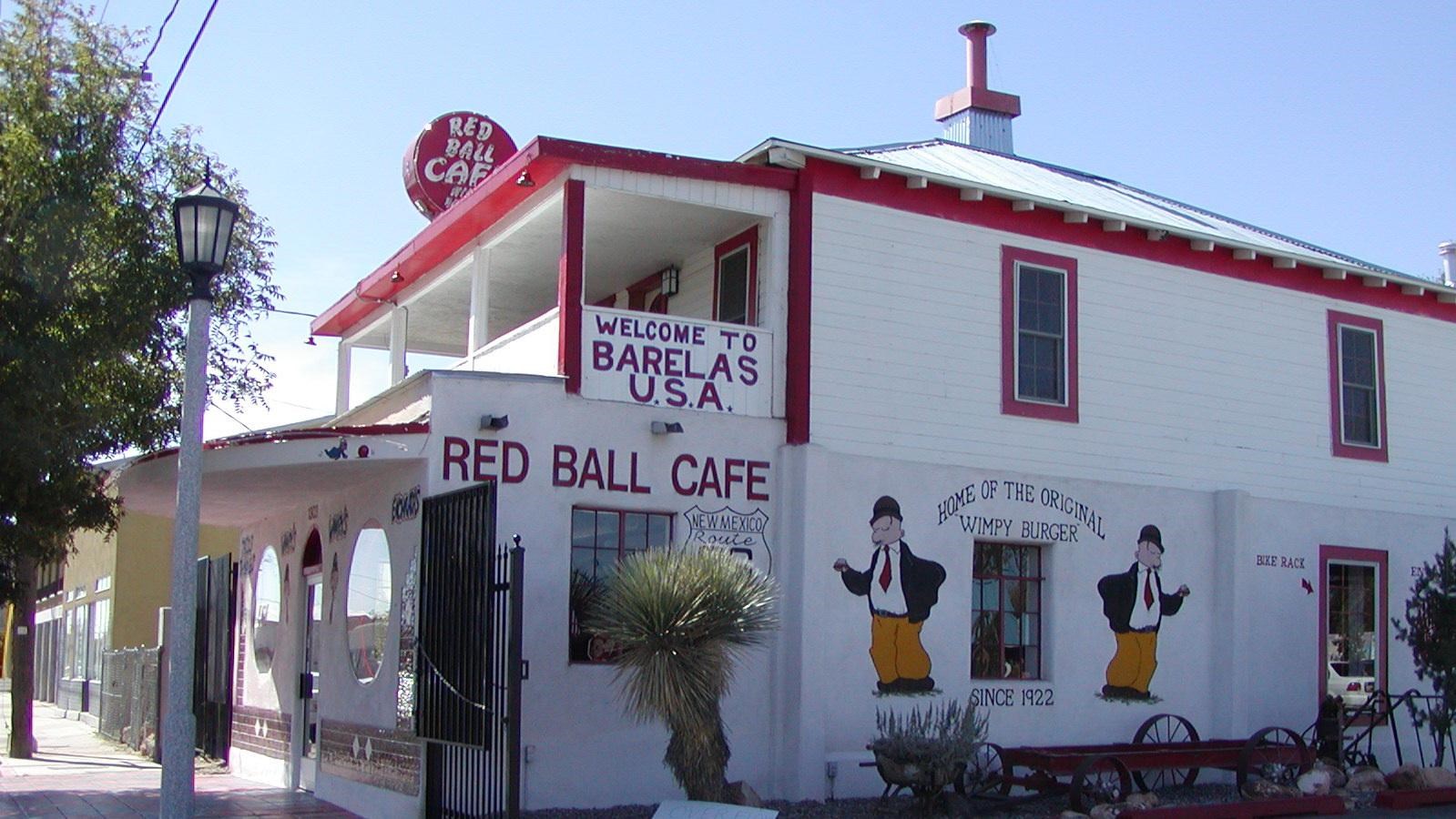 A white two story building with red trim and a sign that reads 