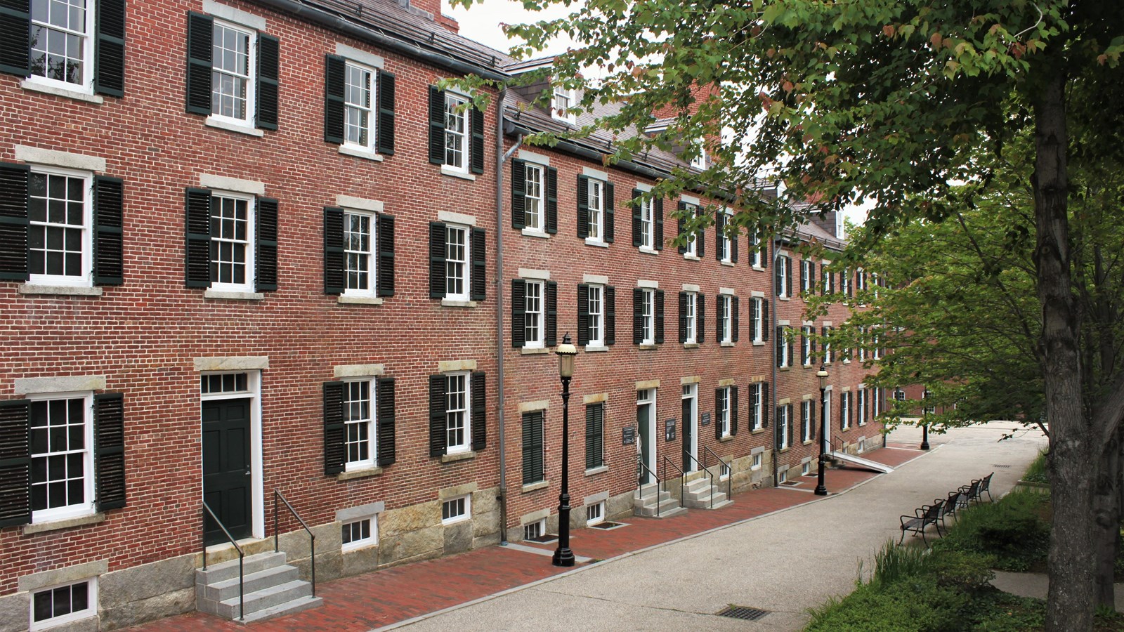 A long brick building with many windows and a few doors.