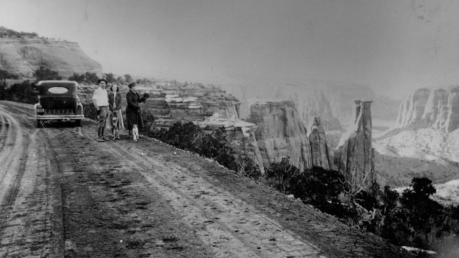 Dirt road curls through photo from lower left to upper right. To the right canyons can be seen.