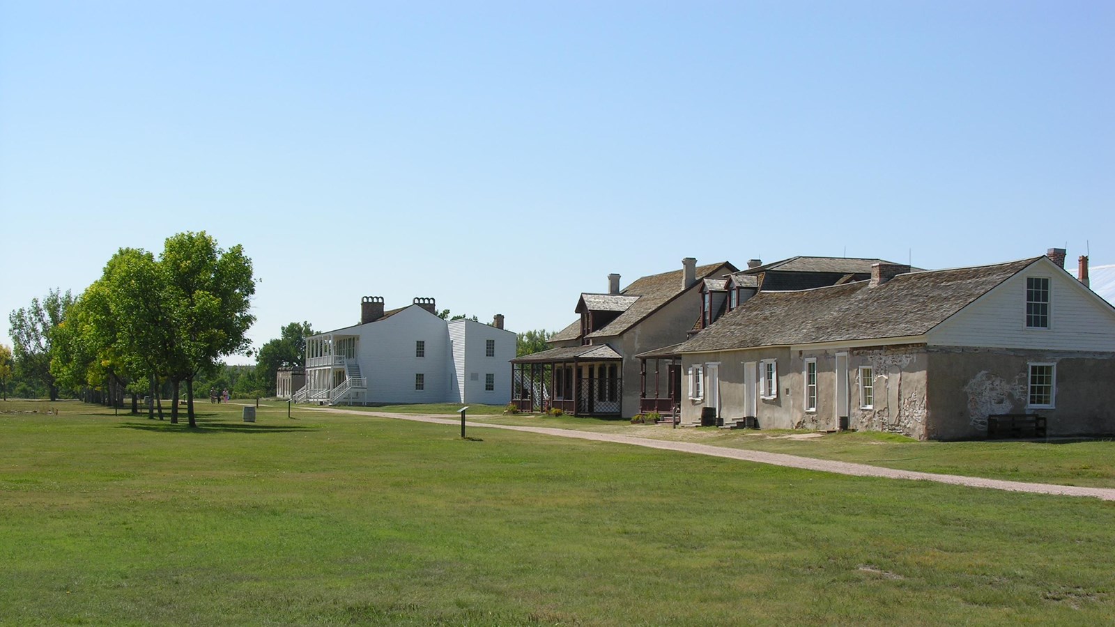 A green lawn stretches out to a historic two story structure.