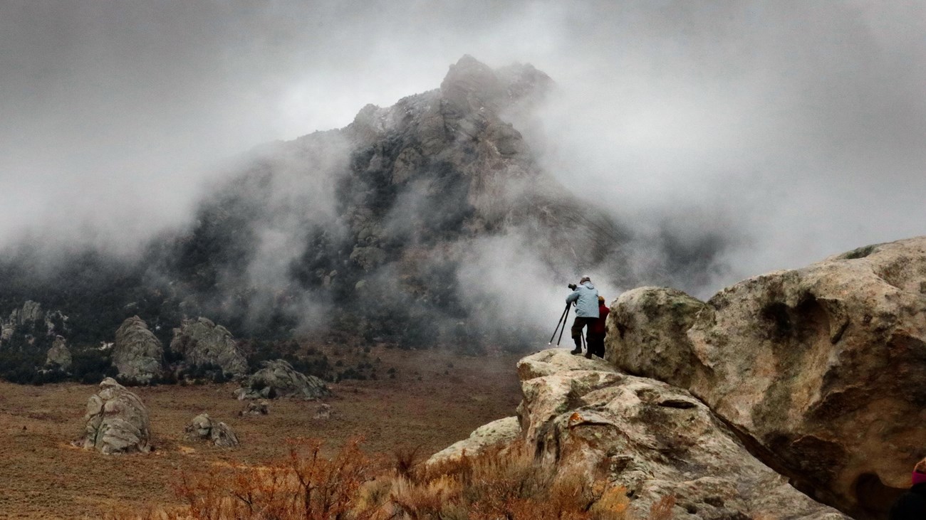 Photographers set up for a dramatic picture of storm clouds swirling around granite spires.