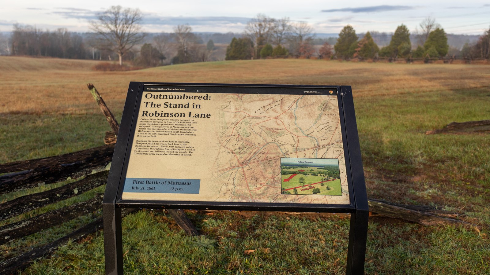 An informational panel in front of a grassy field. 