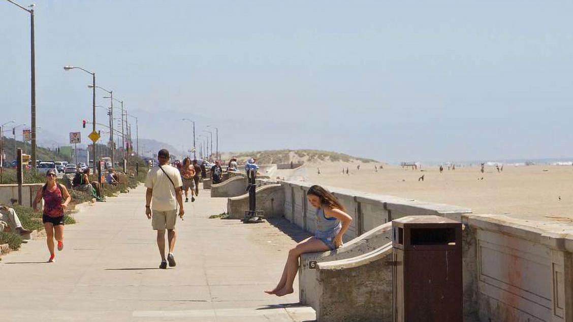 Beach goers walk the concrete promenade at Sloat Blvd.