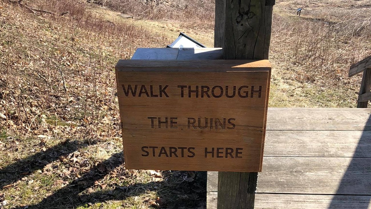 A wooden sign that says a Walk Through the Ruins starts here.