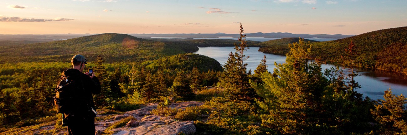 Visitors photographs a sunset over a lake