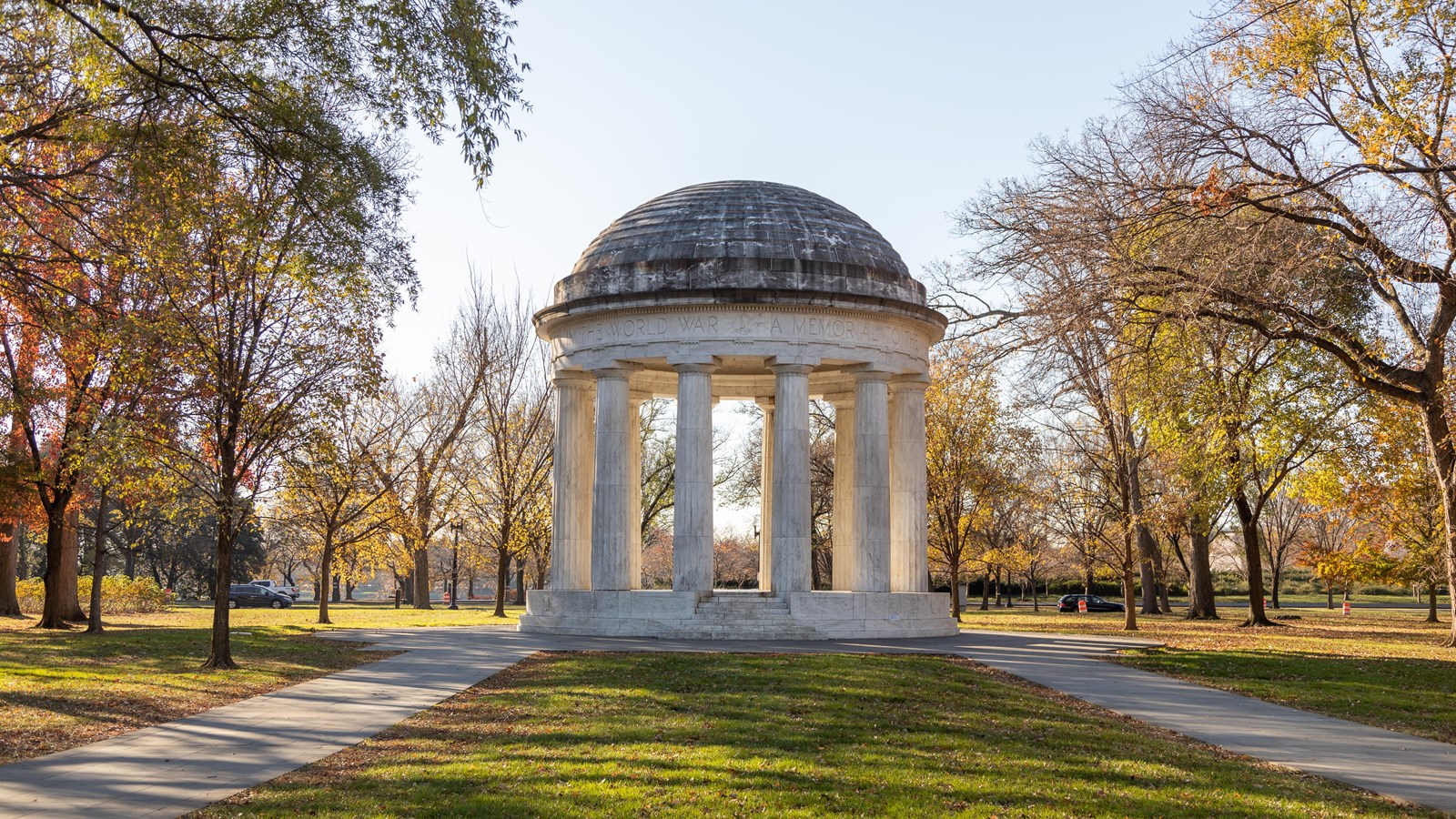 A circle of white columns topped with a dome, flanked by trees.