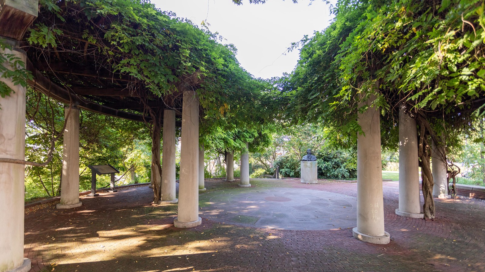 A series of large white pillars with green foliage on top.