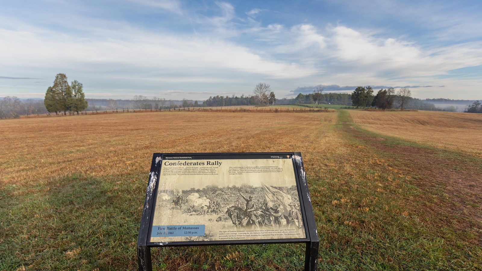 An informational panel in front of a grassy field. 