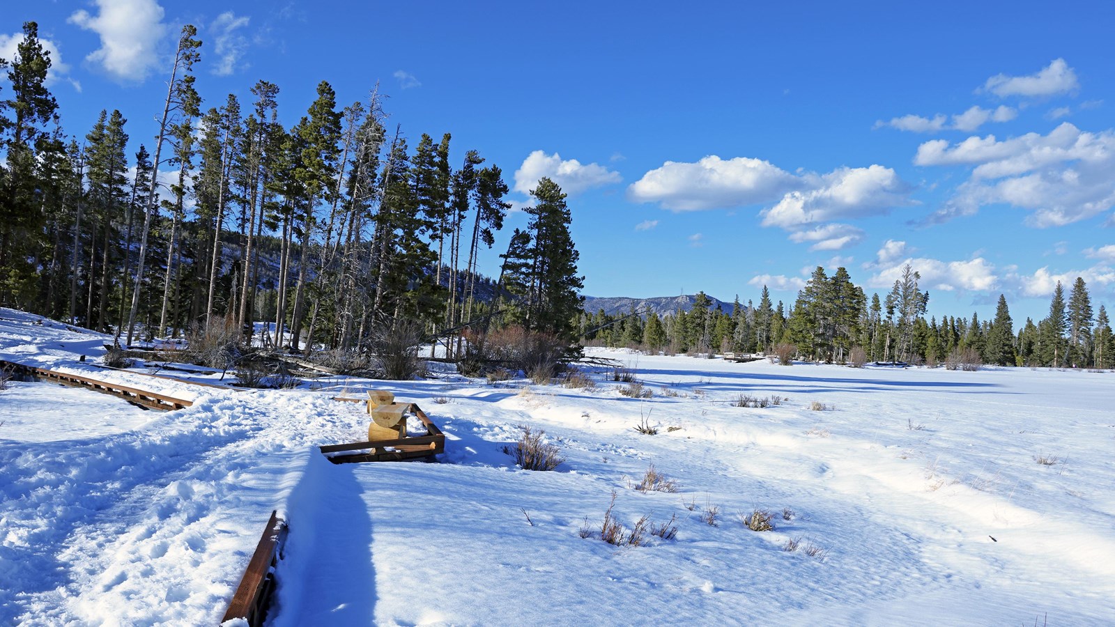 A section of the Sprague Lake Trail and lake is covered with snow