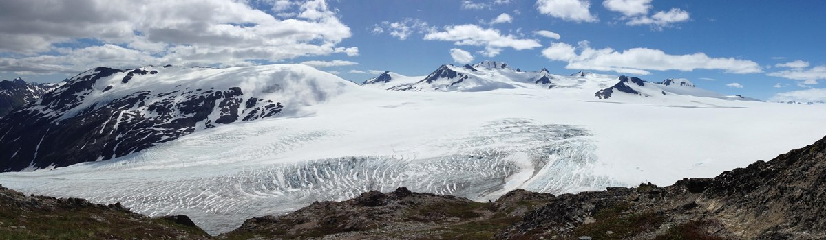 View of a glacier and icefield with mountains in the background. 