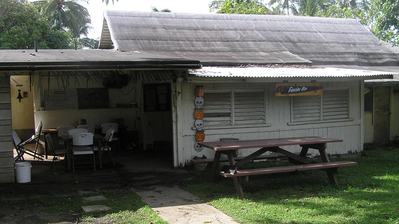 A white house with a picnic table, open garage, and sign that reads Fuesania Bar