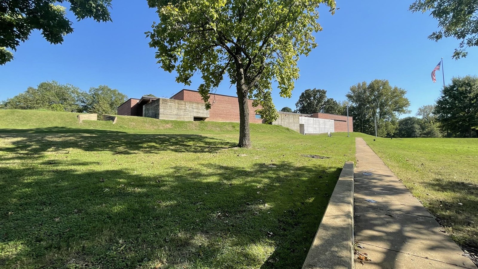 Image of a sidewalk leading up to a brick and concrete building.